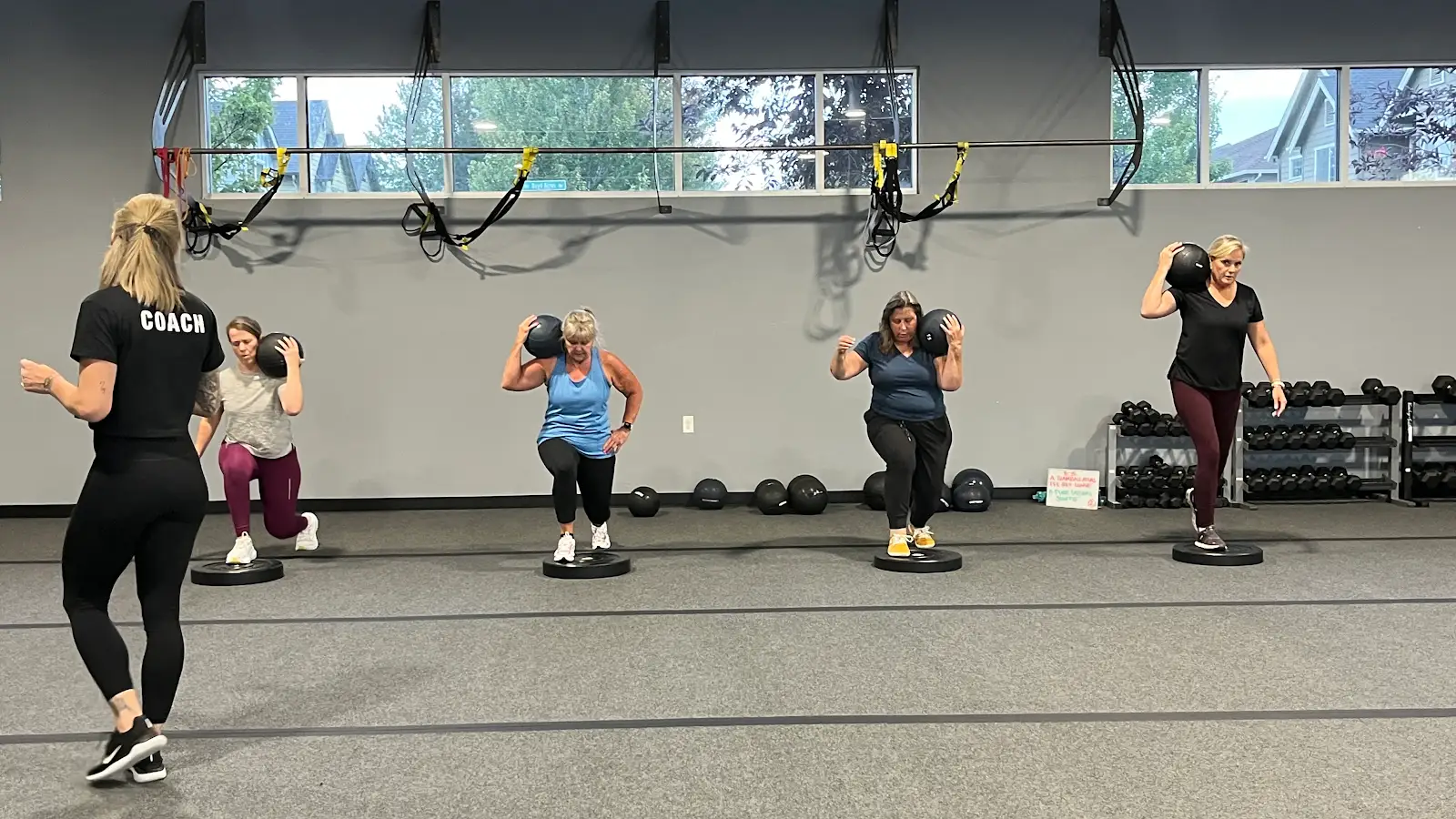 A coach leading members through a sandbag lunge
